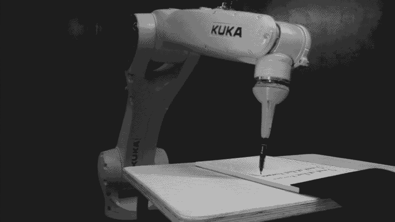 bras robotique installé sur une table d'écolier qui recopie du texte