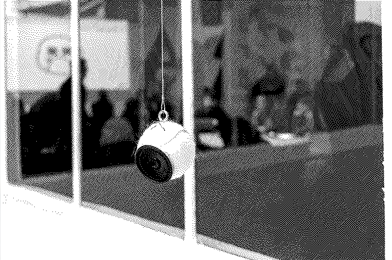 une balle de tennis transformée en enceinte est suspendue au plafond d'une galerie