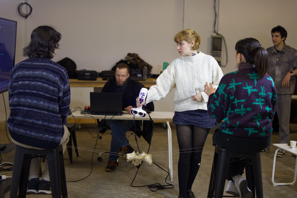 une étudiante scan un os entourée des autres étudiants du workshop